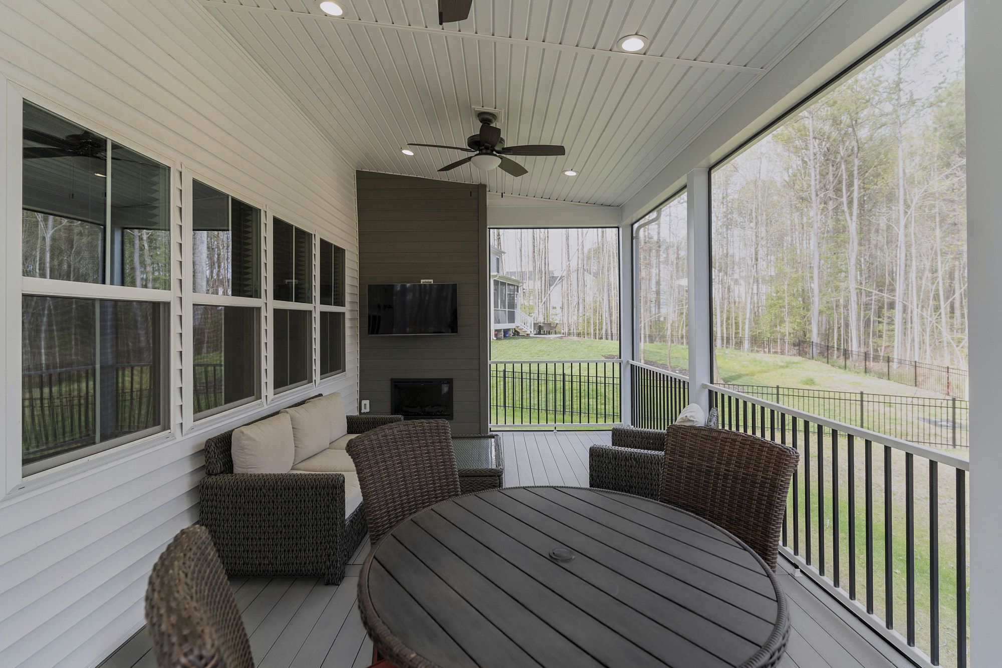 Custom Screened Porch With Wicker Furniture Ceiling Fan Tv And Railing For Cozy Outdoor Entertainment