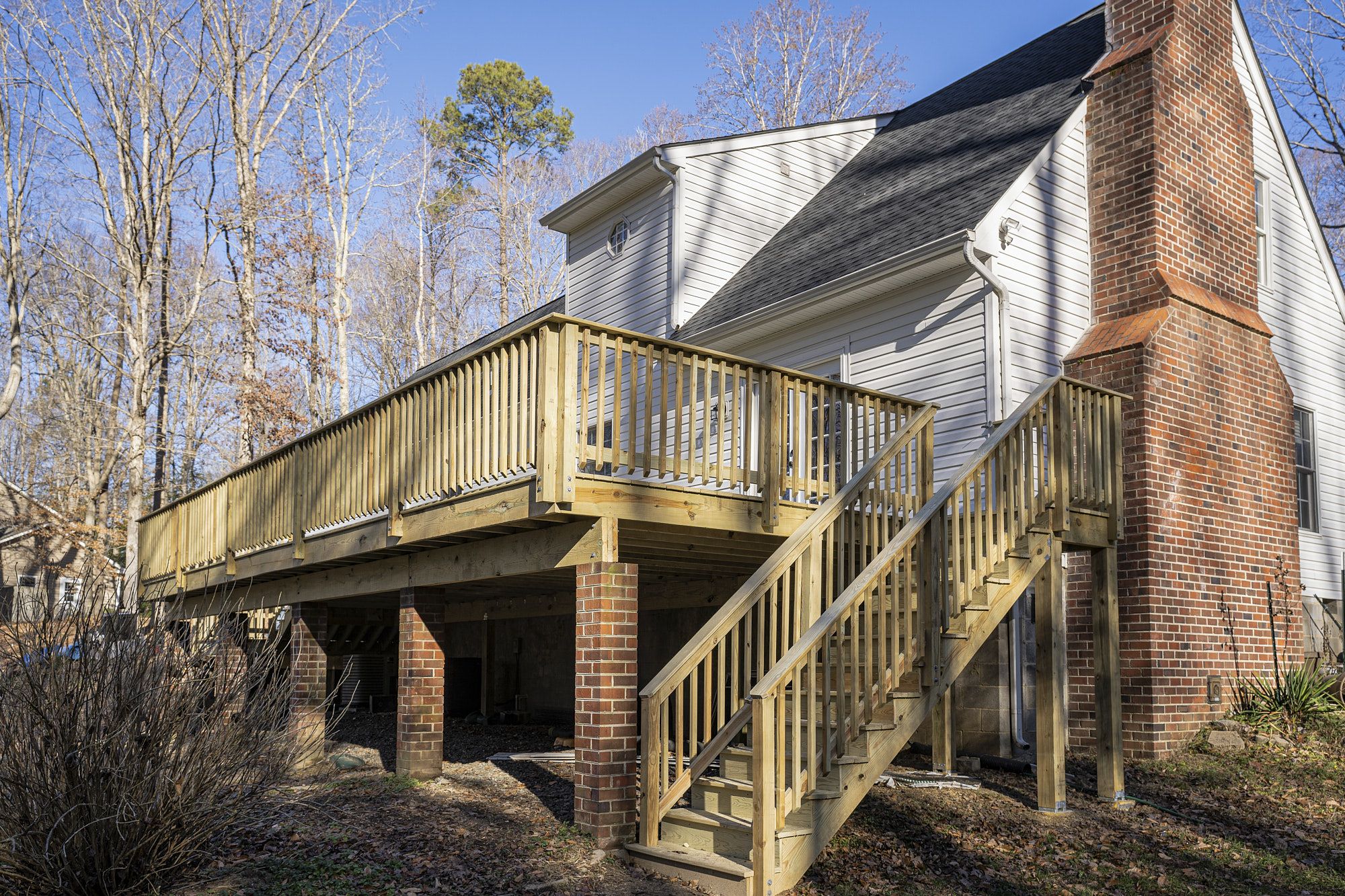 Elevated Wooden Deck With Railing Stairs And Brick Support Columns For Sturdy Outdoor Entertaining Space