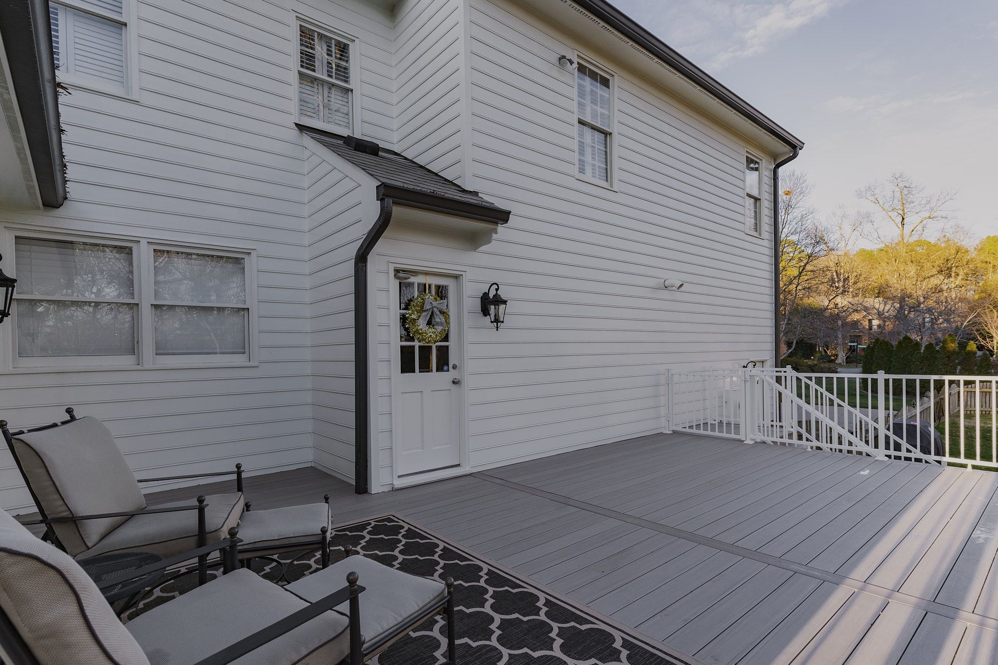 Composite Deck With Seating Area White Railing And Access Door For Outdoor Living And Entertainment